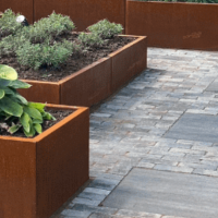 <p><strong>Tijdloze elegantie: Cortenstaal plantenbakken als kunstwerk in je tuin</strong></p>

<p>Stel je voor: een tuin vol leven en kleur, waarin elegante plantenbakken van cortenstaal de natuurlijke schoonheid van je planten versterken. Cortenstaal plantenbakken zijn meer dan alleen een praktische manier om je planten te tonen; ze zijn ware kunstwerken die tijd en natuur samenbrengen in een harmonieus geheel.</p>

<p>De warme, roestige tint van cortenstaal geeft een bijzondere charme aan elke tuin, terras of balkon. Naarmate de tijd verstrijkt, ontwikkelt het materiaal een prachtige patina die elk exemplaar uniek maakt. Het robuuste staal weerstaat de elementen en wordt met de jaren steeds mooier, waardoor je plantenbakken niet alleen functioneel zijn, maar ook een artistiek accent vormen.</p>

<p>Deze plantenbakken passen zich perfect aan diverse stijlen aan: van strakke, moderne tuinen tot landelijke, natuurlijke omgevingen. Ze bieden voldoende ruimte voor bloemen, struiken of kleine boompjes en zorgen voor een mooie, natuurlijke afbakening of accentuering van je buitenruimte. Het open ontwerp bevordert de ventilatie, wat de gezondheid van je planten ten goede komt.</p>

<p>Wat ze extra bijzonder maakt, is hun veelzijdigheid en duurzaamheid. Ze vragen weinig onderhoud en worden door de natuurlijke ontwikkeling van de patina nog mooier met de jaren. Elke plantbak vertelt zijn eigen verhaal, net als de tuin waarin ze staan.</p>

<p>Met cortenstaal plantenbakken haal je niet alleen een functioneel element in huis, maar ook een tijdloos kunstwerk dat je buitenruimte verrijkt met karakter, warmte en natuurlijke schoonheid. Een perfecte combinatie van design en duurzaamheid, die jouw tuin of terras een eigen, unieke uitstraling geeft.</p>
