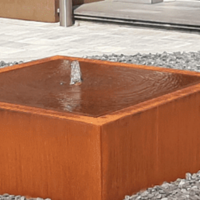 <p><strong>De tijdloze elegantie van een cortenstaal watertafel</strong></p>

<p>Stel je een buitenruimte voor waar rust en natuurlijke schoonheid samenkomen, een plek waar het zachte geluid van stromend water een kalmerend effect heeft. Een cortenstaal watertafel vormt het perfecte middelpunt van zo&rsquo;n sfeer, een harmonieus samenspel tussen design, natuur en duurzaamheid.</p>

<p>Deze watertafel, vervaardigd uit robuust cortenstaal, straalt een eigentijdse industri&euml;le uitstraling uit die zich na verloop van tijd ontwikkelt tot een warme, roestkleurige patina. Elke tafel is uniek, met subtiele variaties en texturen die het houtachtige karakter van het materiaal benadrukken. Het is een ontwerp dat de tand des tijds doorstaat en met de natuur meegroeit.</p>

<p>Wat deze tafel zo bijzonder maakt, is niet alleen haar esthetiek, maar ook haar rustgevende werking. Het kabbelende water dat zachtjes stroomt, cre&euml;ert een serene sfeer en brengt een gevoel van harmonie in elke tuin of patio. Het geluid van het water verbindt je met de natuur en nodigt uit tot ontspanning en reflectie.</p>

<p>Daarnaast is een cortenstaal watertafel zeer duurzaam en onderhoudsvriendelijk. Het materiaal weerstaat alle weersomstandigheden en krijgt door de jaren heen alleen maar meer karakter. De waterpartij zelf kan worden aangepast met LED-verlichting, fonteinen of natuurlijke elementen, waardoor je jouw eigen persoonlijke oase kunt cre&euml;ren.</p>

<p>Een cortenstaal watertafel is niet zomaar een tuinaccessoire &mdash; het is een kunstwerk, een rustpunt en een natuurlijke eyecatcher die je buitenruimte verrijkt. Het brengt een stukje natuur en tijdloze elegantie samen, en zorgt voor een unieke sfeer die je keer op keer weer inspireert.</p>
